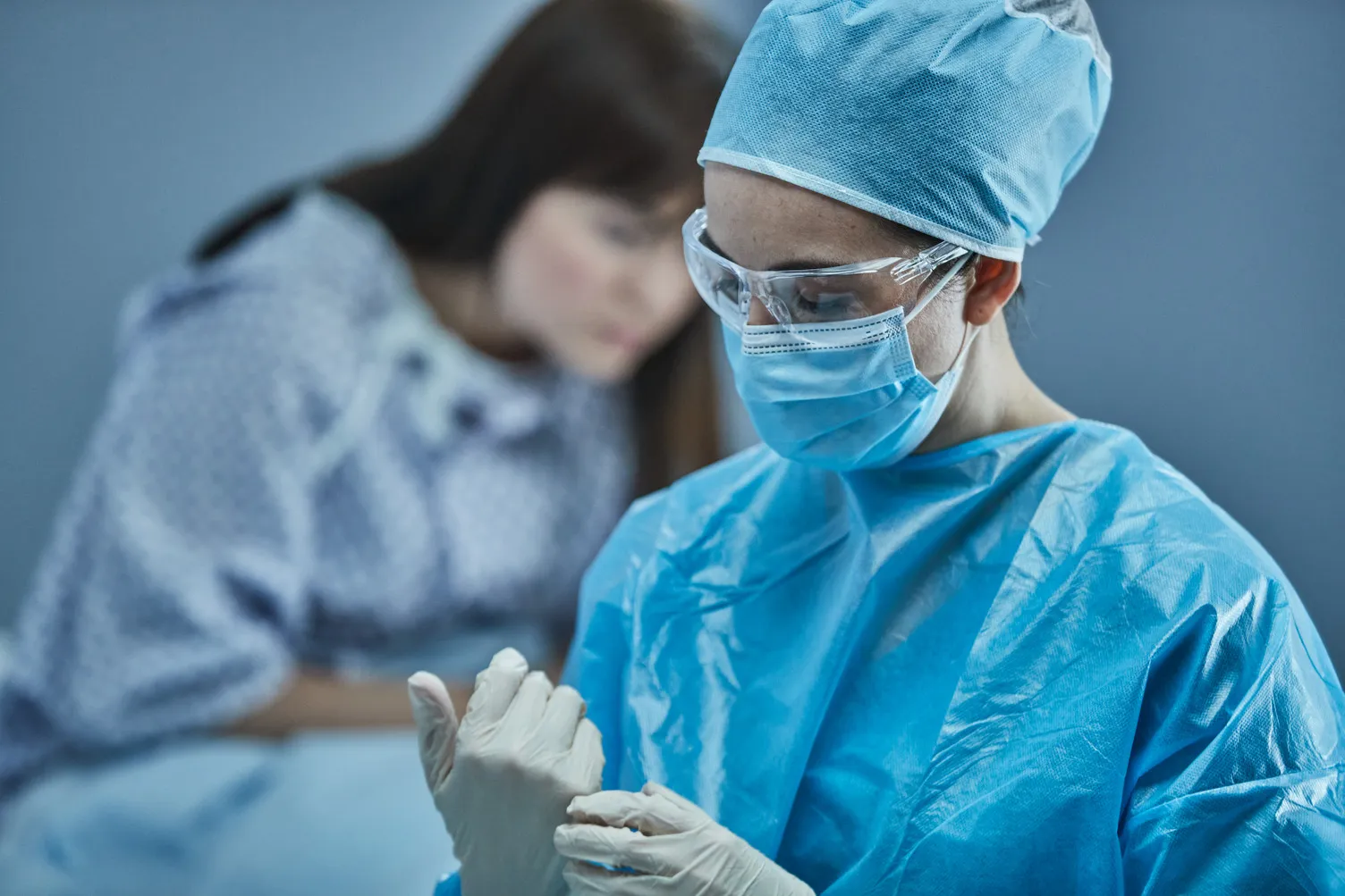 病院のガウンを着た女性患者の前にいる医師が、手術用の服を着用している。