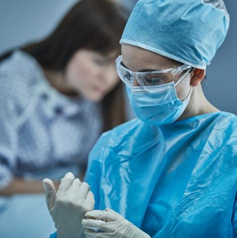 病院のガウンを着た女性患者の前にいる医師が、手術用の服を着用している。